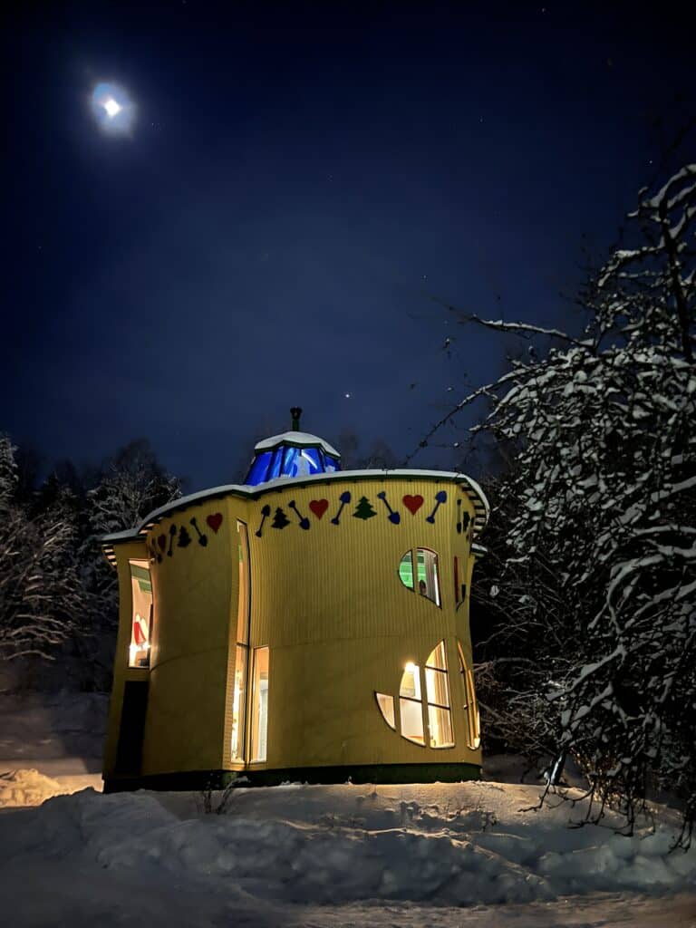 Värikäs keltainen, lehden muotoinen talo jossa on lehden muotoiset ikkunat yöllä.