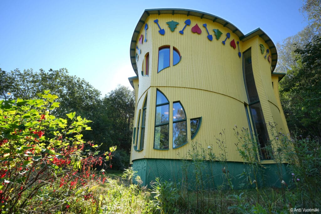 Värikäs keltainen, lehden muotoinen talo jossa on lehden muotoiset ikkunat.